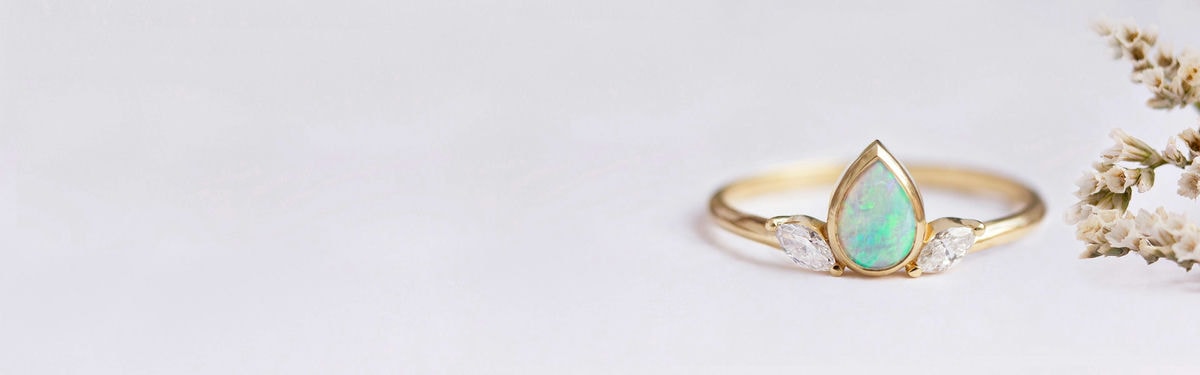 anillo de compromiso con cabujón de ópalo y dos diamantes talla marquesa