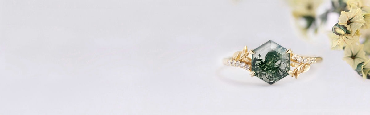 Hojas y ramas en un anillo de compromiso inspirado en la naturaleza con piedra preciosa hexagonal de ágata musgosa.