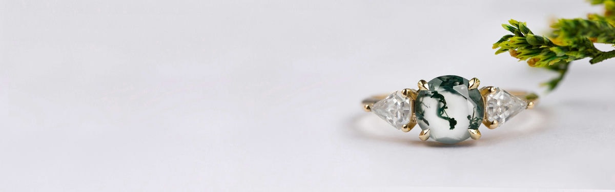 dva kulaté diamanty a kulatý mechový achát tvoří zásnubní prsten se třemi kameny