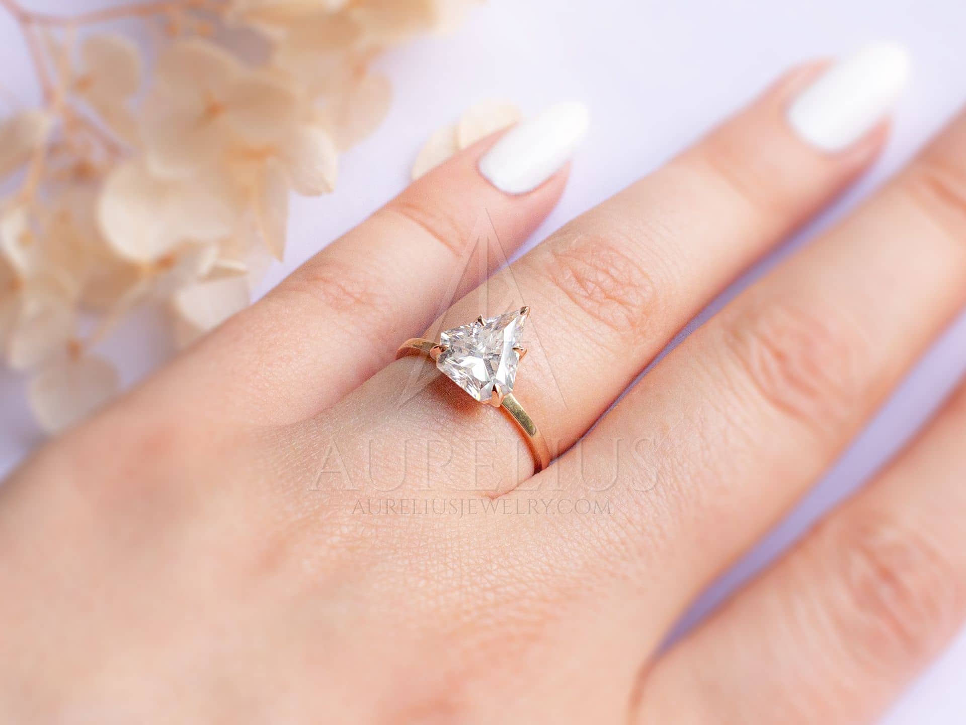 https://aureliusjewelry.com/wp-content/uploads/elegant-colorless-moissanite-solitaire.ring-on-finger.jpg