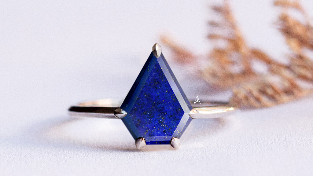 shield shape lapis lazuli on an engagement ring with claw prong settings