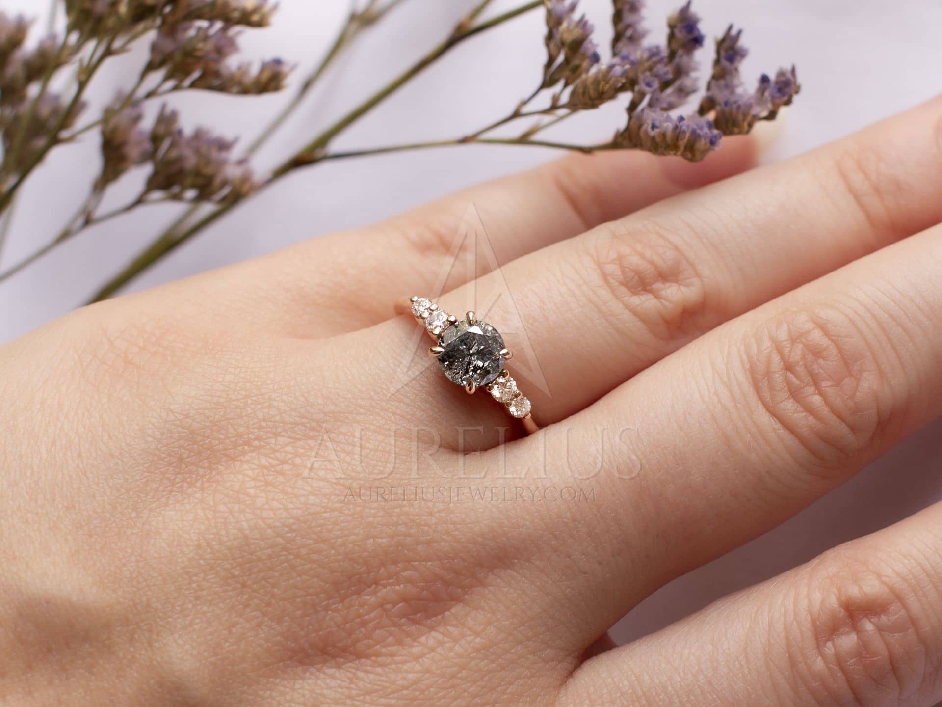 https://aureliusjewelry.com/wp-content/uploads/round-salt-pepper-diamond-ring-two-side-stones-hand.jpg