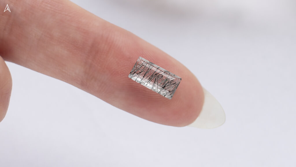 rutilated quartz baguette on a finger for transparency inspecting