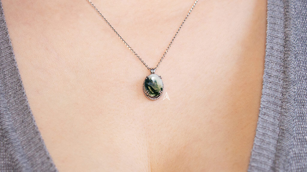 woman wearing a necklace with moss agate oval gemstone